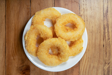 Fried shrimp donut in white plate on wooden table.