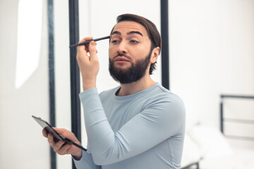 Transgender person applying the eyeshadows to his upper eyelid