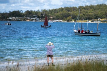 man watching wooden boat on the water, at the wooden boat festival in hobart tasmania australia