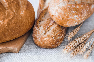 Fresh delicious bread close-up. Freshly baked sourdough bread with a golden crust on a wooden board. The context of a bakery with delicious bread. Confectionery products.