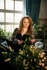 portrait of a beautiful brunette smiling woman with flowers in vintage room