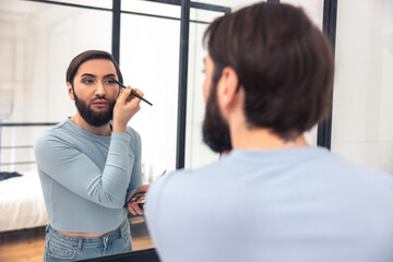 Guy looking at the mirror during the eye makeup application