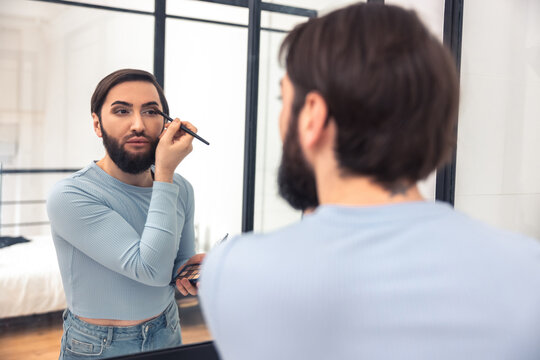 Guy looking at the mirror during the eye makeup application