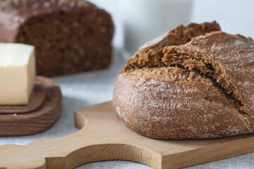 Fresh delicious bread close-up. Freshly baked sourdough bread with a golden crust on a wooden board. The context of a bakery with delicious bread. Confectionery products.
