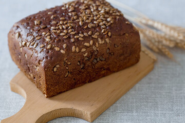 Fresh delicious whole grain rye bread with seeds close-up. Freshly baked bread on a wooden board. The context of a bakery with delicious bread. Confectionery products.