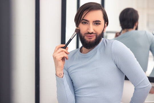 Transgender person powdering his face in the bathroom