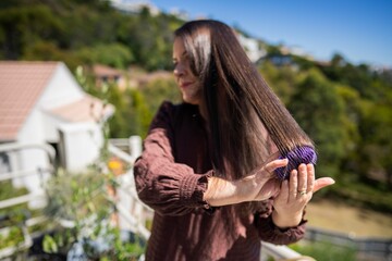 Beautiful girl brushing hair, model styling black hair getting ready to go out to an event