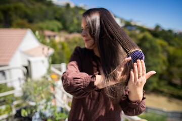 Beautiful girl brushing hair, model styling black hair getting ready to go out to an event