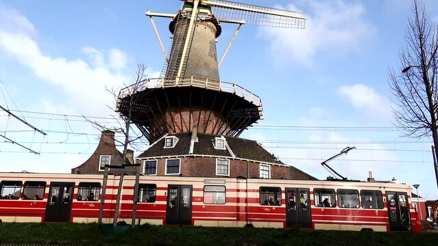 Delft, Netherlands A tram rides by an old windmill in the center of town, the Delft Windmill de Roos or Molen de Roos.