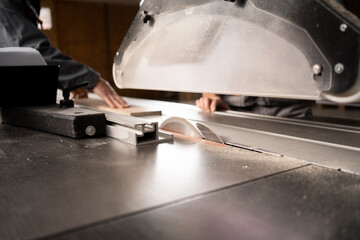 Carpenters working at furniture factory workshop on sliding panel saw sawing fibreboard. Production, manufacture and woodworking industry concept.