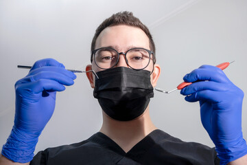 dental instruments in the hands of the doctor. dentist in sterile latex gloves holding dental tools. close-up. dentist conducts an examination of the patient's oral cavity. bottom view. 