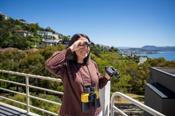 Girl using binoculars on a balcony in a city next to the sea, seaside town