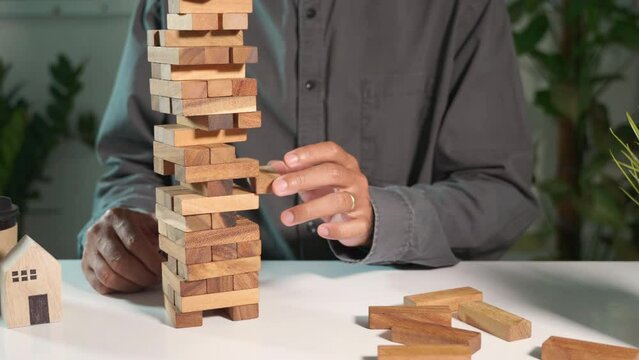Business fail danger building tower challenge game building. Businessman hand pulling out wood block and failed the tower is falling down he wrong strategy decision