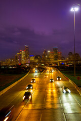Fototapeta na wymiar Houston Downtown City Skyline in Golden Color at night over Interstate 45 Freeway in Texas, USA, vibrant metropolis nightscape with motion blur light trails of cars on the highway