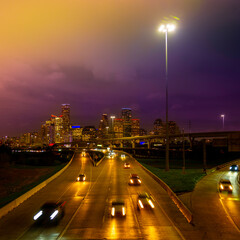Houston Downtown City Skyline in Golden Color at foggy night over Interstate 45 Freeway in Texas, USA, vibrant metropolis nightscape with motion blur light trails of cars on the highway