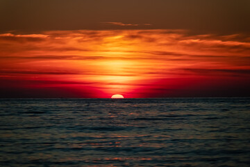 Obraz premium Panoramic sunset view from Sveti Stefan at Adriatic Mediterranean Sea, Budva Riviera, Montenegro, Europe. Reflection of sun beams on water surface during twilight. Summer vacation in seaside resort