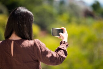 Girl video calling her friends on a zoom call. Woman on holiday skyping her family outside in a beautiful place