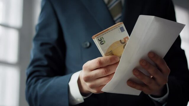 Hands putting euro envelope indoors close up. Business payment wealth concept.