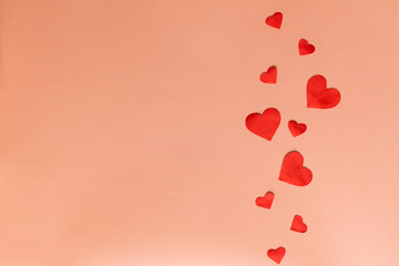 Valentine's day card. Red valentines are scattered on a plain coral background. Place for inscription congratulations