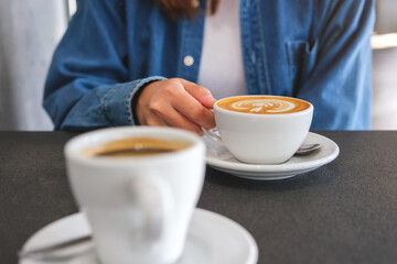 Closeup image of a woman holding and drinking coffee with friend in cafe