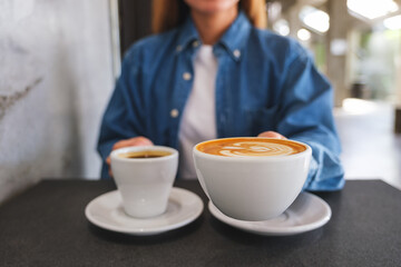 Closeup image of a woman holding and serving two cups of hot coffee