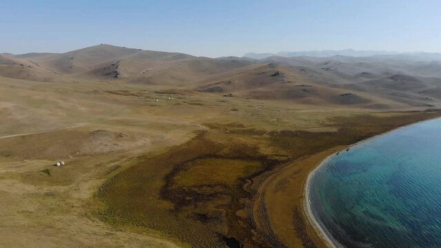 On the shore of a mountain lake in autumn. Traditional place of summer pastures in Kyrgyzstan. On the shore there are yurts in which shepherds live