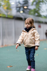Fototapeta premium Little girl playing with swings at the playground