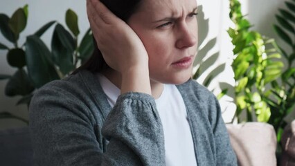 Ears pain concept. Close up of sick young caucasian woman suffering from earache, having otitis illness and healthcare problems, Unhappy millennial lady rubbing sore auricle sitting on sofa at home
