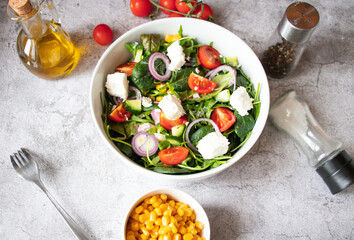 
Green vegan salad from a mixture of green leaves and vegetables. On a gray background