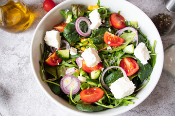 
Green vegan salad from a mixture of green leaves and vegetables. On a gray background