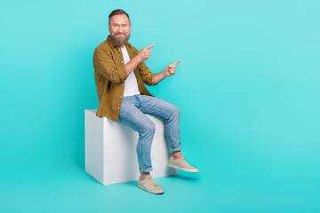 Photo of handsome man worker boss sitting platform arm presenting empty space quality products isolated on cyan color background