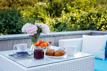 Breakfast table with bread, fresh fruits and strawberries and coffee served on balkony terrace or hotel on summer morning for romantic couple lunch.