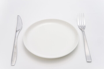 白いテーブルに置かれた白い皿とシルバーのフォークとナイフ