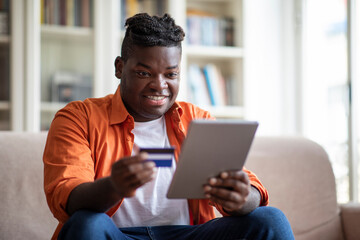 Cheerful african man using digital pad and credit card
