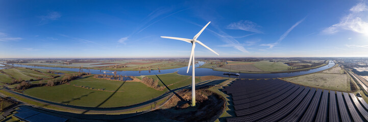 Dutch landscape panorama of wind turbine and solar panels with waterway intersection of river...