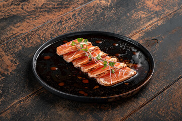 Fillet of fresh smoked salmon sliced on a plate with soy sauce. Asian dish sashimi from raw salmon