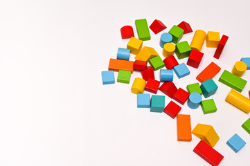 Colorful wooden bricks of different shapes on a white wooden table. The concept of learning. empty space