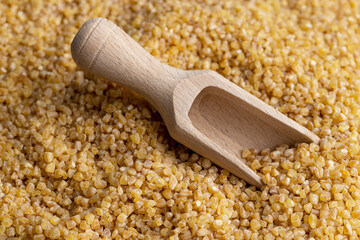 Not cooked wheat porridge with a wooden spoon