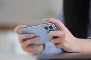 Young woman watching videos on mobile phone. Close up photo of unrecognizable female person playing online mobile game with a smart phone