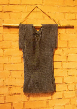 Old military chain mail to protect a warrior hangs on a brick wall, antique.
