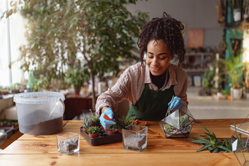 Happy smiling woman florist making succulent plant composition at floral design studio
