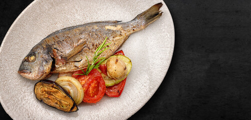 Fried dorado fish, in a plate, with grilled vegetables