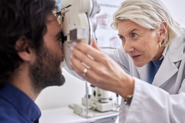 Doctor with a man in vision test or eye exam for eyesight by a focused senior optometrist or ophthalmologist. Optician helping check retina health of a client or happy customer with medical insurance