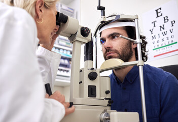 Eye exam, vision test and patient with laser lens and doctor at optometry consultation. Face of a man and woman healthcare person with machine for eyes, wellness and health insurance with expert care - obrazy, fototapety, plakaty