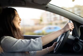 An Asian woman driving a car and smiling happily with a positive expression during the travel trip,people enjoy the transportation of laughter and relaxed happy woman in the concept of travel vacation