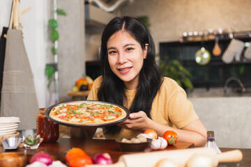 Young attractive Asian woman talking communicating during online live streaming how to cook homemade pizza indoor kitchen. content creator using camera recording food product review.