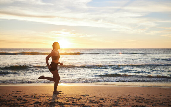 Woman, fitness and running on the beach sunset for healthy cardio exercise, training or workout in the outdoors. Female runner exercising in sunrise for run, health and wellness by the ocean coast