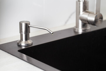Dispenser in the kitchen built into the sink for dish detergent. Copy space for text, decor
