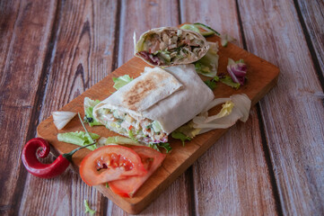 shawarma with chicken on a wooden board with tomatoes and salad and white sauce various options