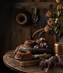 Homemade chocolate bundt cakes with berries on wooden table.Delicious dessert photo in rustic style.